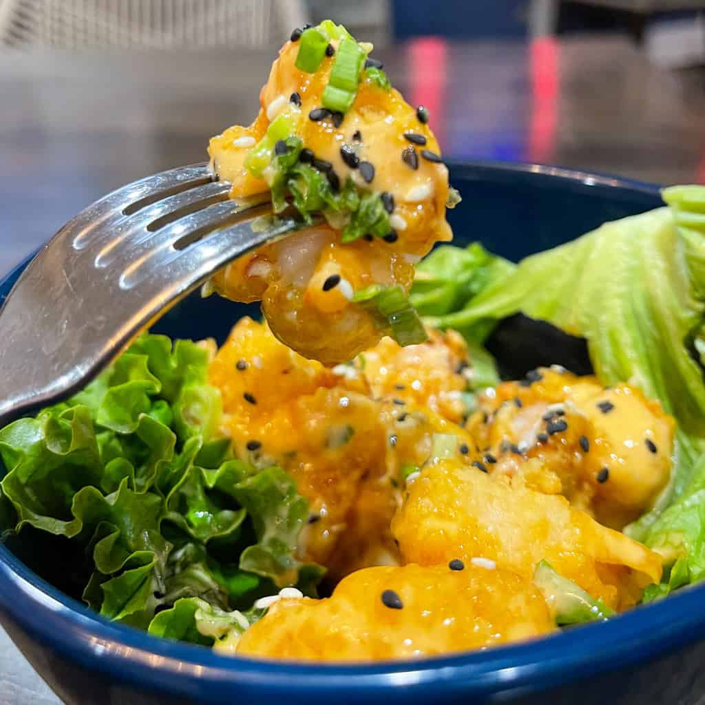 Bang Bang Shrimp - Crispy shrimp coated with creamy Asian remoulade and sesame seeds on a bed of greens