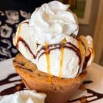 Chocolate chip cookie lava cake with vanilla ice cream and whipped cream topped with chocolate and caramel sauce